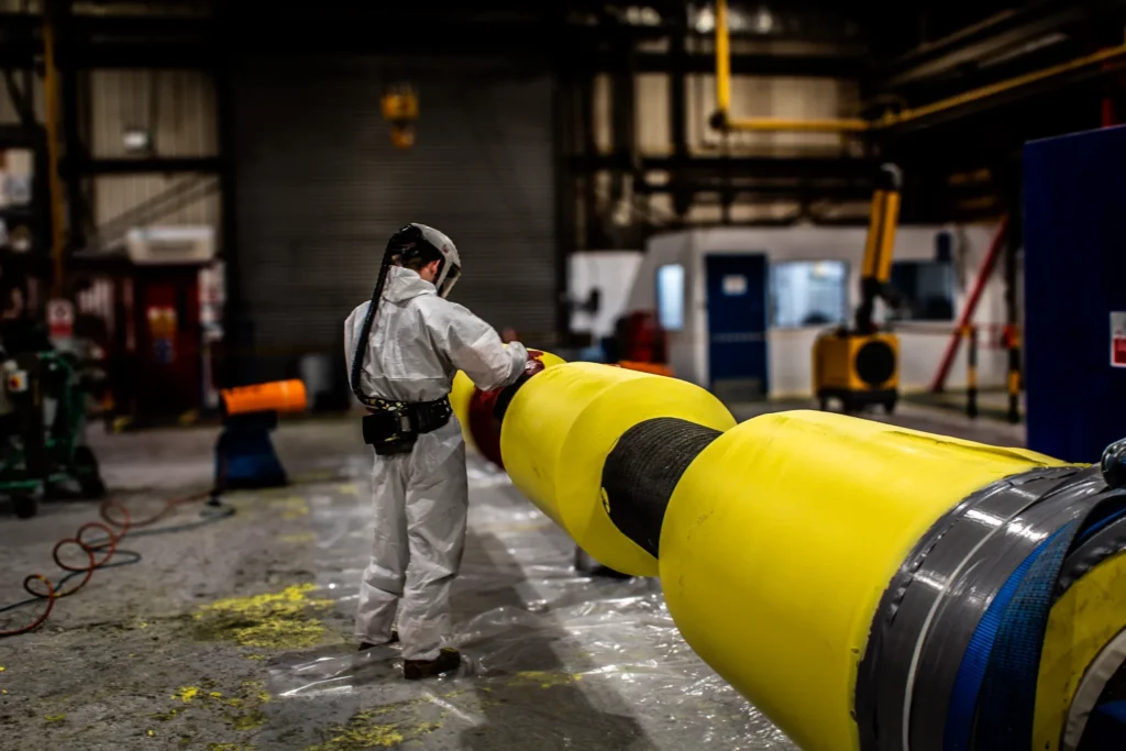 LJF technician in full PPE inspecting polyurethane thermal insulation coating on subsea pipe