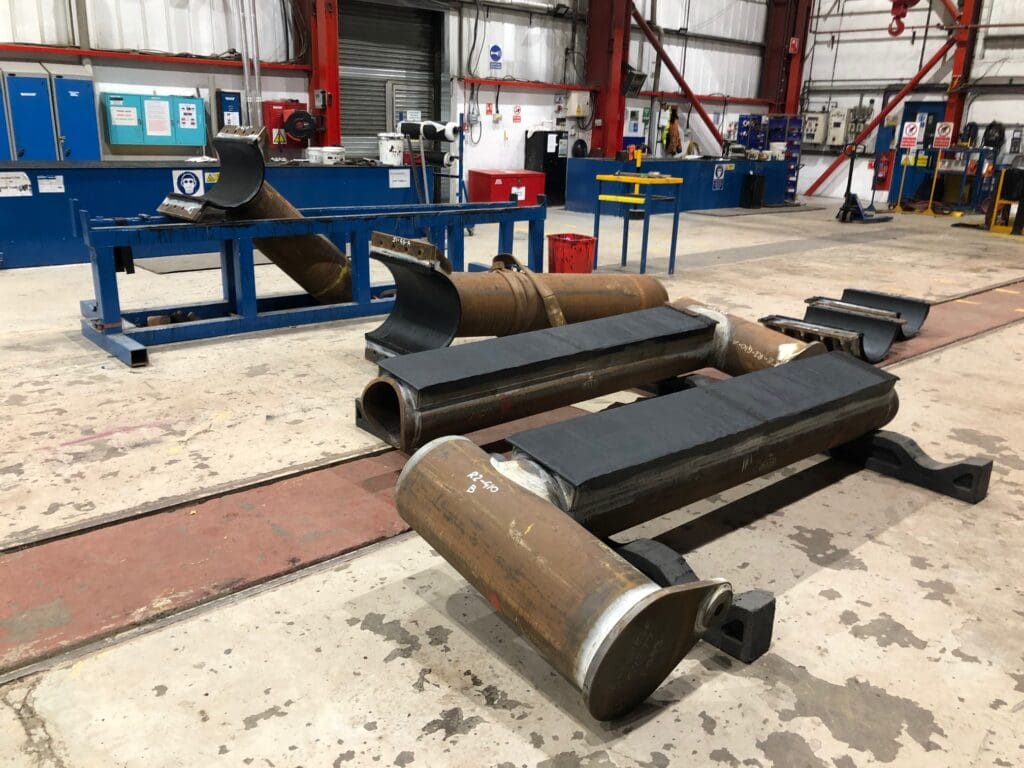 Steel half-shell and clamp-style components with black inner coatings staged in workshop at LJF Custom Coatings