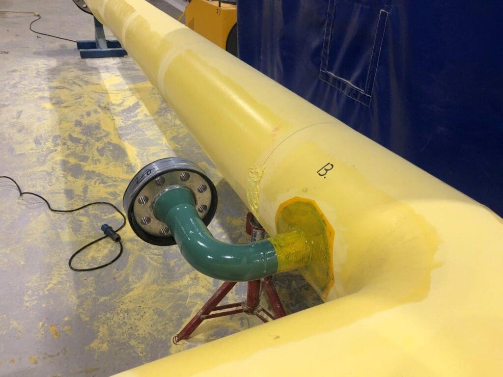 Close-up of a yellow PU thermal insulated pipe with green flanged branch outlet, showing detailed coating application at LJF Custom Coatings