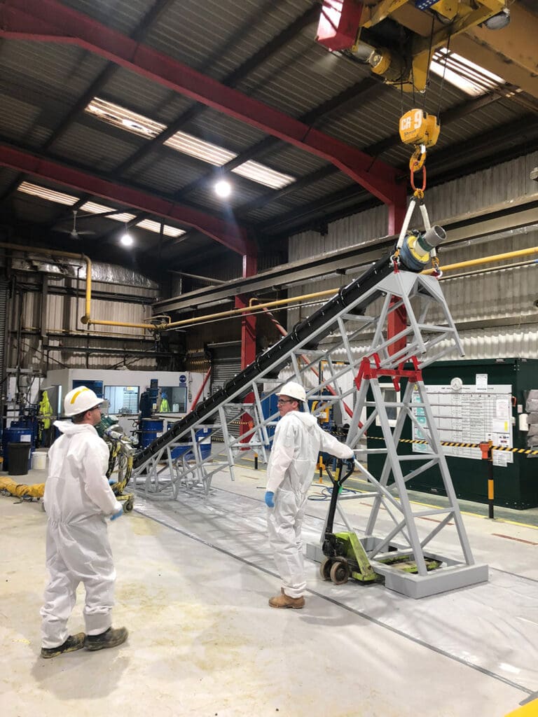 LJF Custom Coatings technicians preparing coated pipework in workshop with overhead crane and support frame